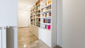 Ein Flur mit einem weißen Bücherregal voller Bücher, einer weißen Heizung und einem gefliesten Boden.