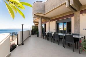 Un balcone con zona pranzo, vista sul mare e un edificio dalla facciata decorata.