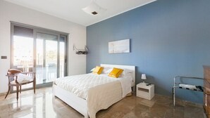 Ein Schlafzimmer mit einem Bett, einem Nachttisch, einem Sessel und einem Fenster mit Jalousien.