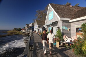 A wooden boardwalk with a row of buildings, including a restaurant with a blue sign. - BIS-Duck Resort - Large 3BR/3BA - Great Pools and Beach! (Duck)