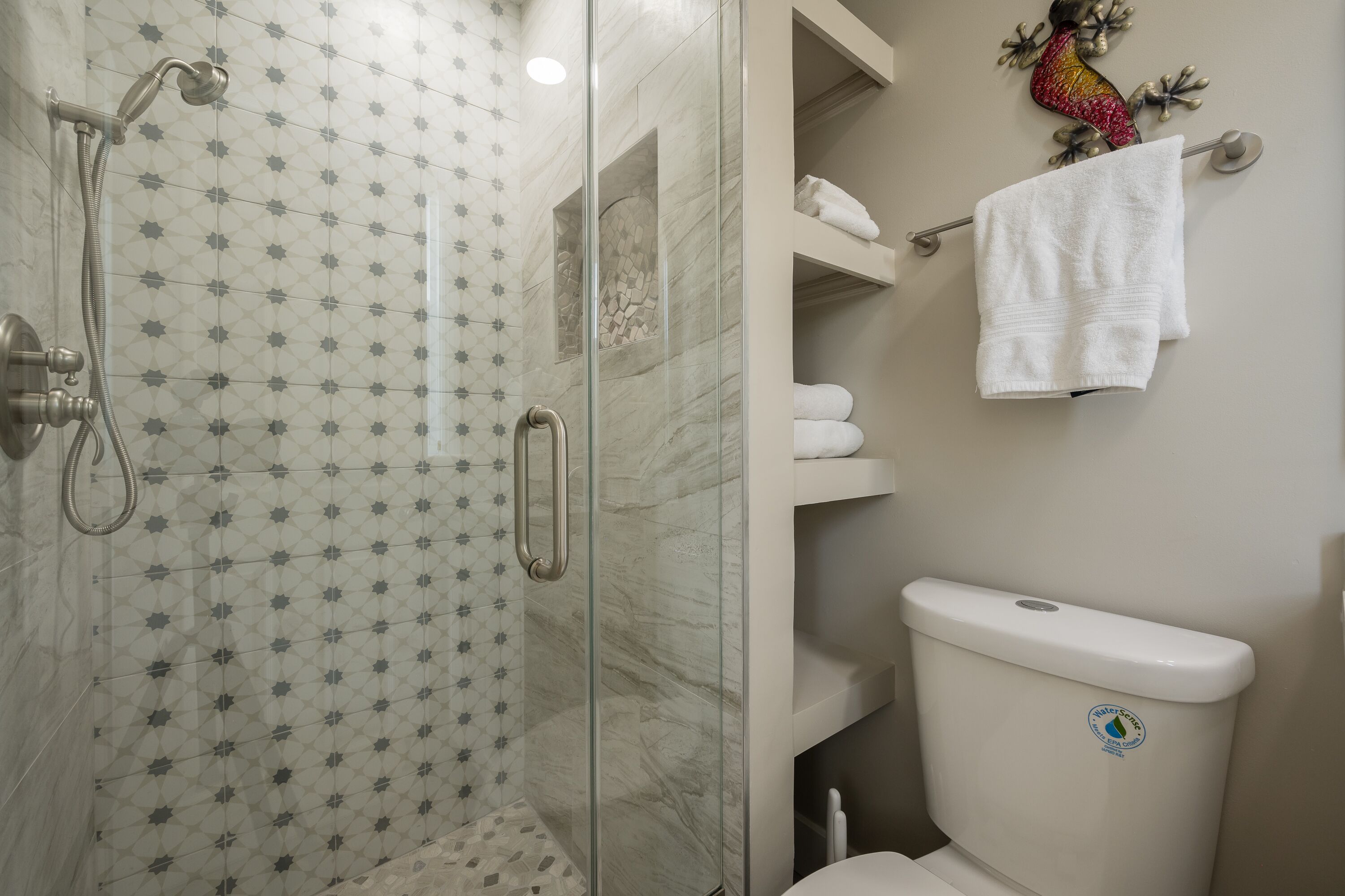 A bathroom with a glass-enclosed shower, a toilet, and a towel rack.