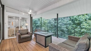 A covered outdoor area with wicker furniture, a table, and a view of dense greenery. - ♥ Mission Ridge Midcentury - Family Friendly - Valley Views -  High Speed Wifi (Rossville)