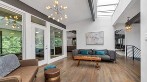 A spacious living area with a modern sofa, a wooden coffee table, and a large window offering a view of greenery. - ♥ Mission Ridge Midcentury - Family Friendly - Valley Views -  High Speed Wifi (Rossville)