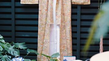 A traditional Japanese garment hanging on a wooden structure, surrounded by potted plants and decorative items.