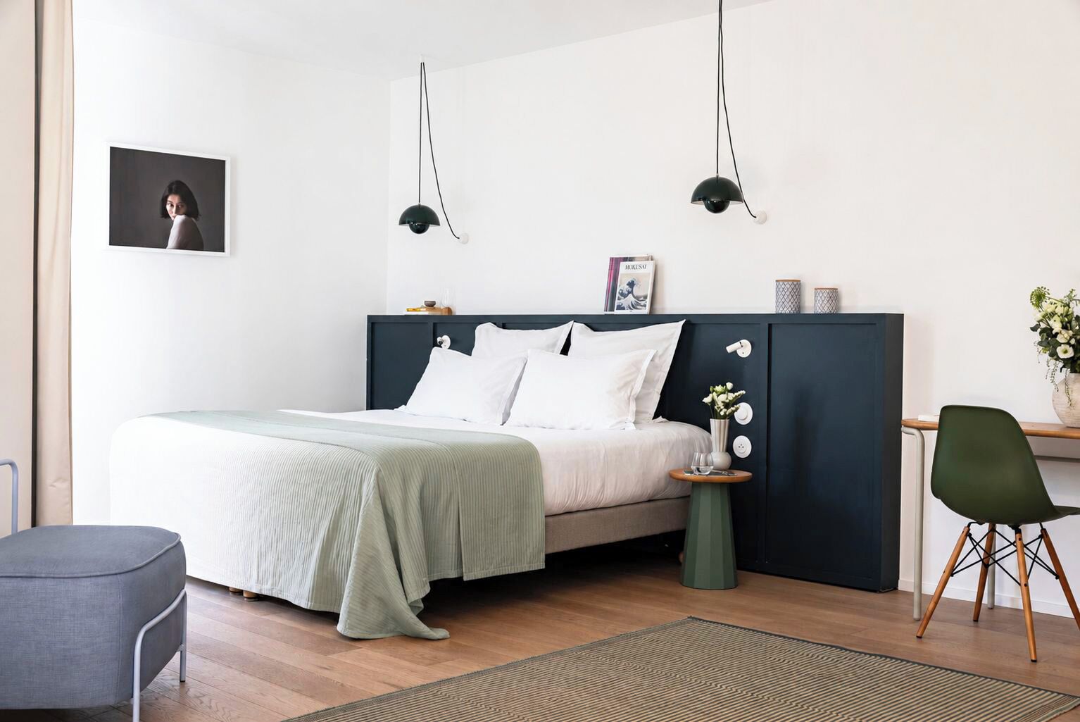Ein modernes Schlafzimmer mit Bett, Nachttischen, einem Sessel und einem Schreibtisch.