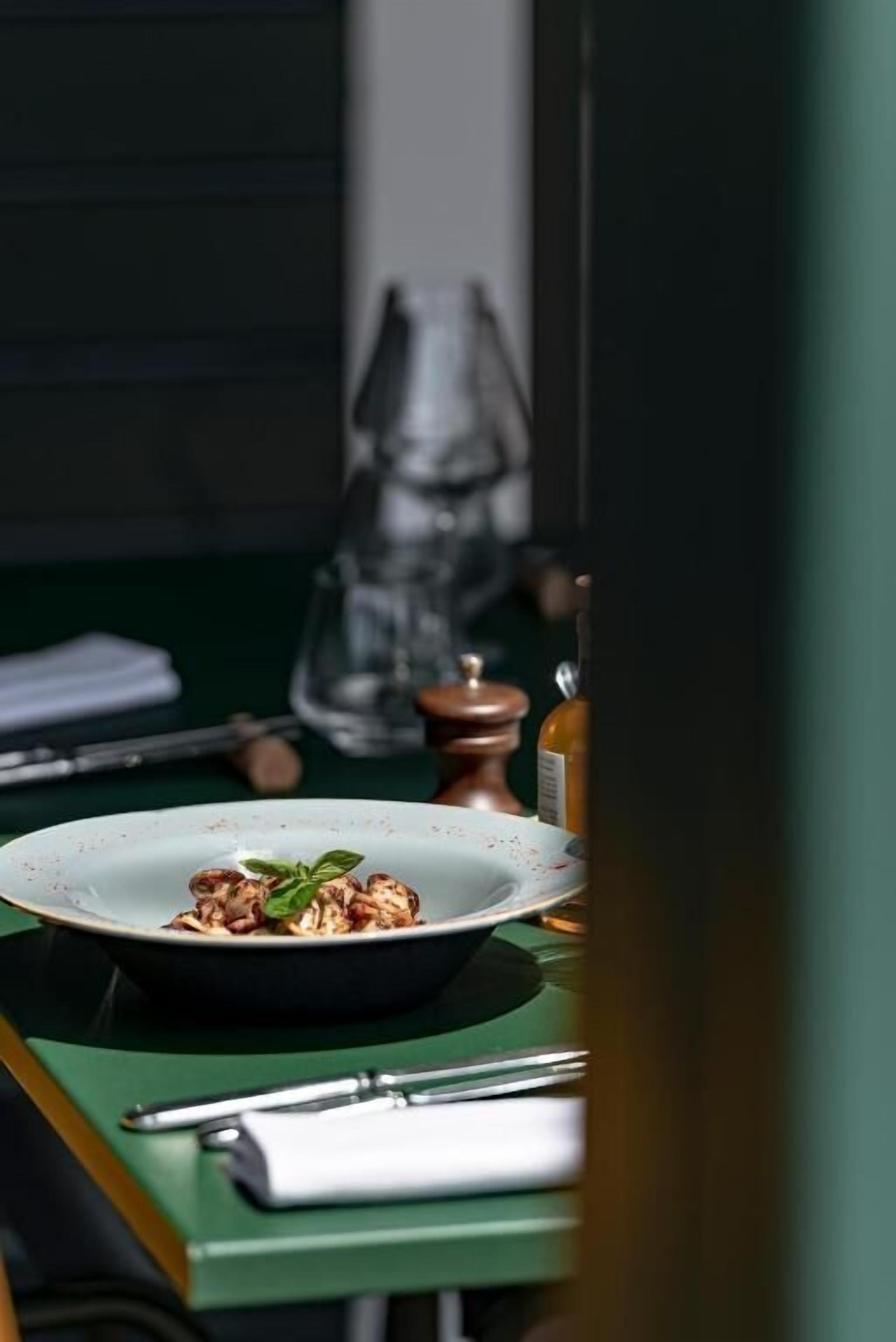Une table à manger avec une assiette de nourriture, un verre et un moulin à poivre.