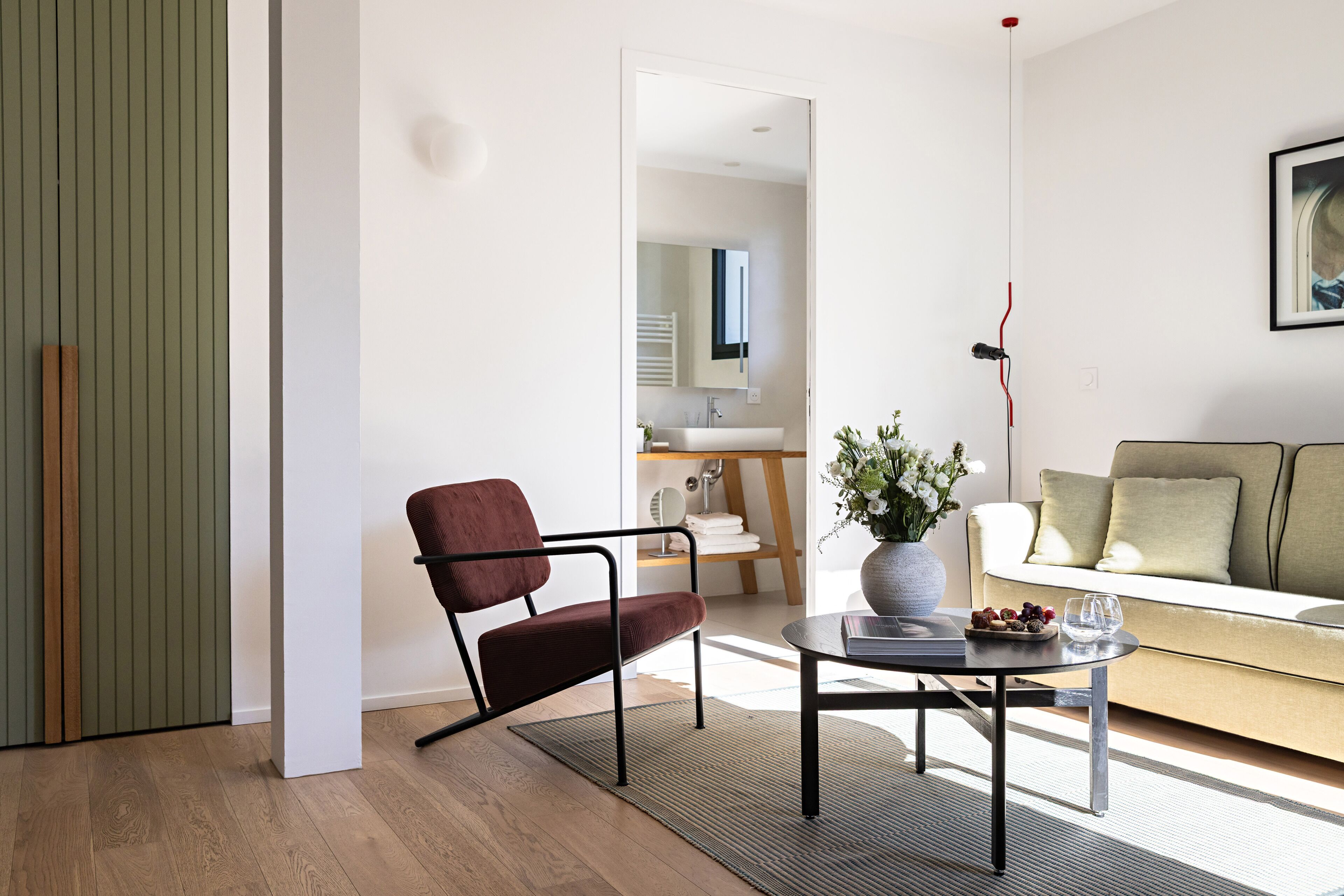 Un salon moderne avec un canapé, un fauteuil, une table basse et un vase rempli de fleurs.