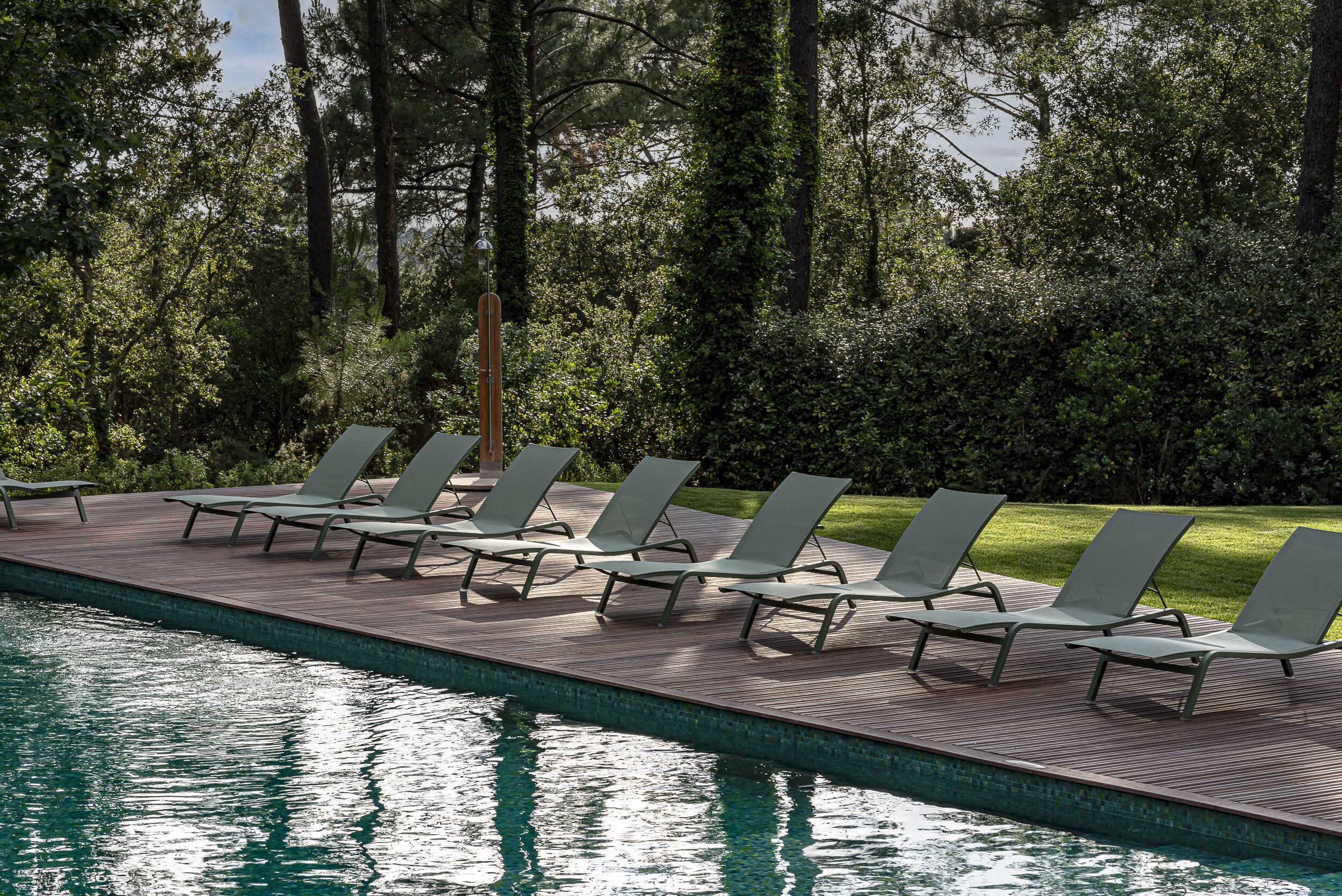 A poolside area with lounge chairs and a wooden deck.