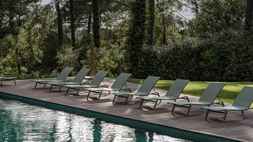 A poolside area with lounge chairs and a wooden deck.