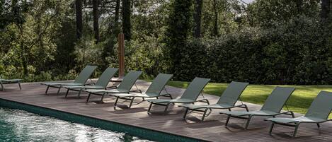 A poolside area with lounge chairs and a wooden deck.
