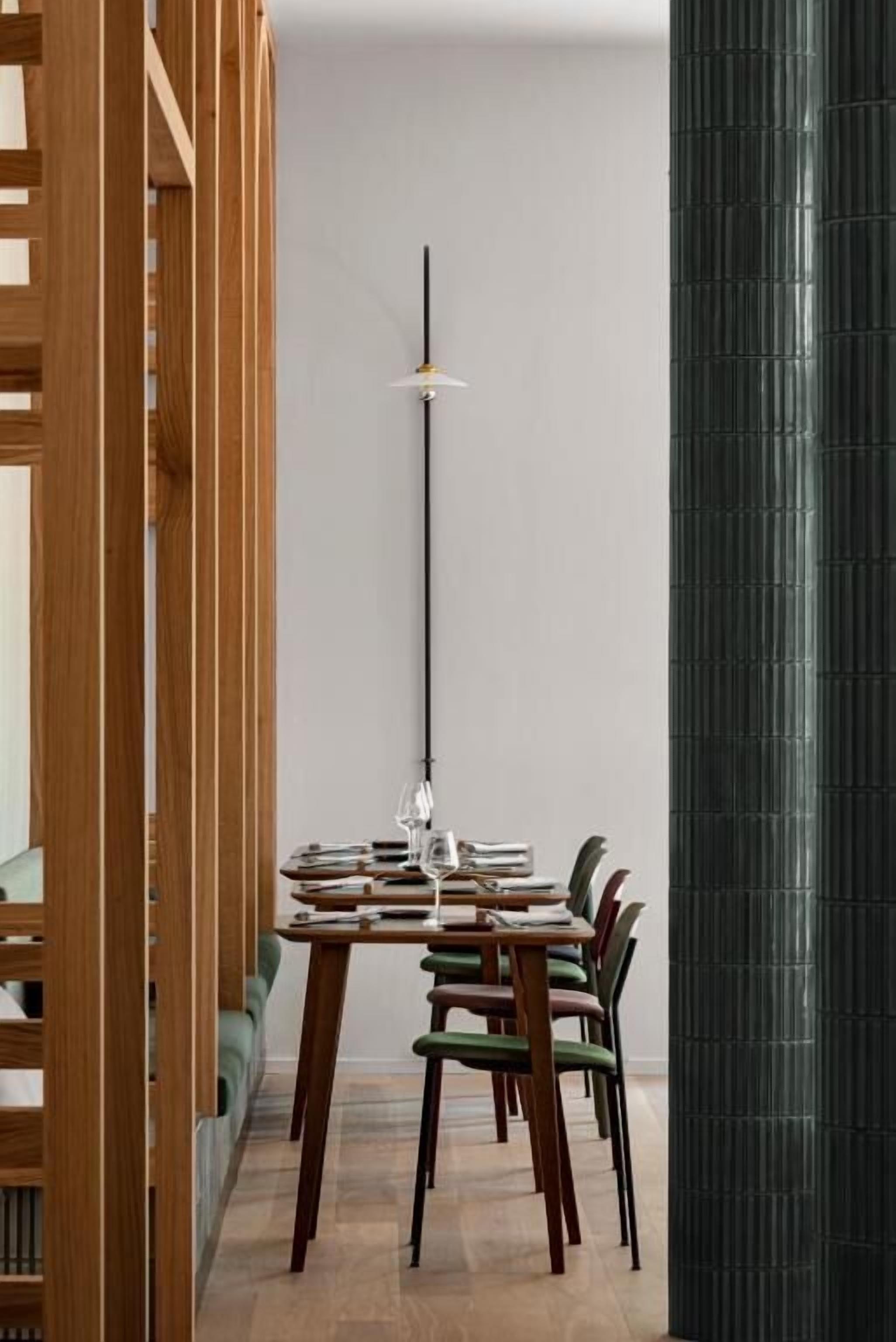 A modern dining area with a wooden table, chairs, and a tall black column.