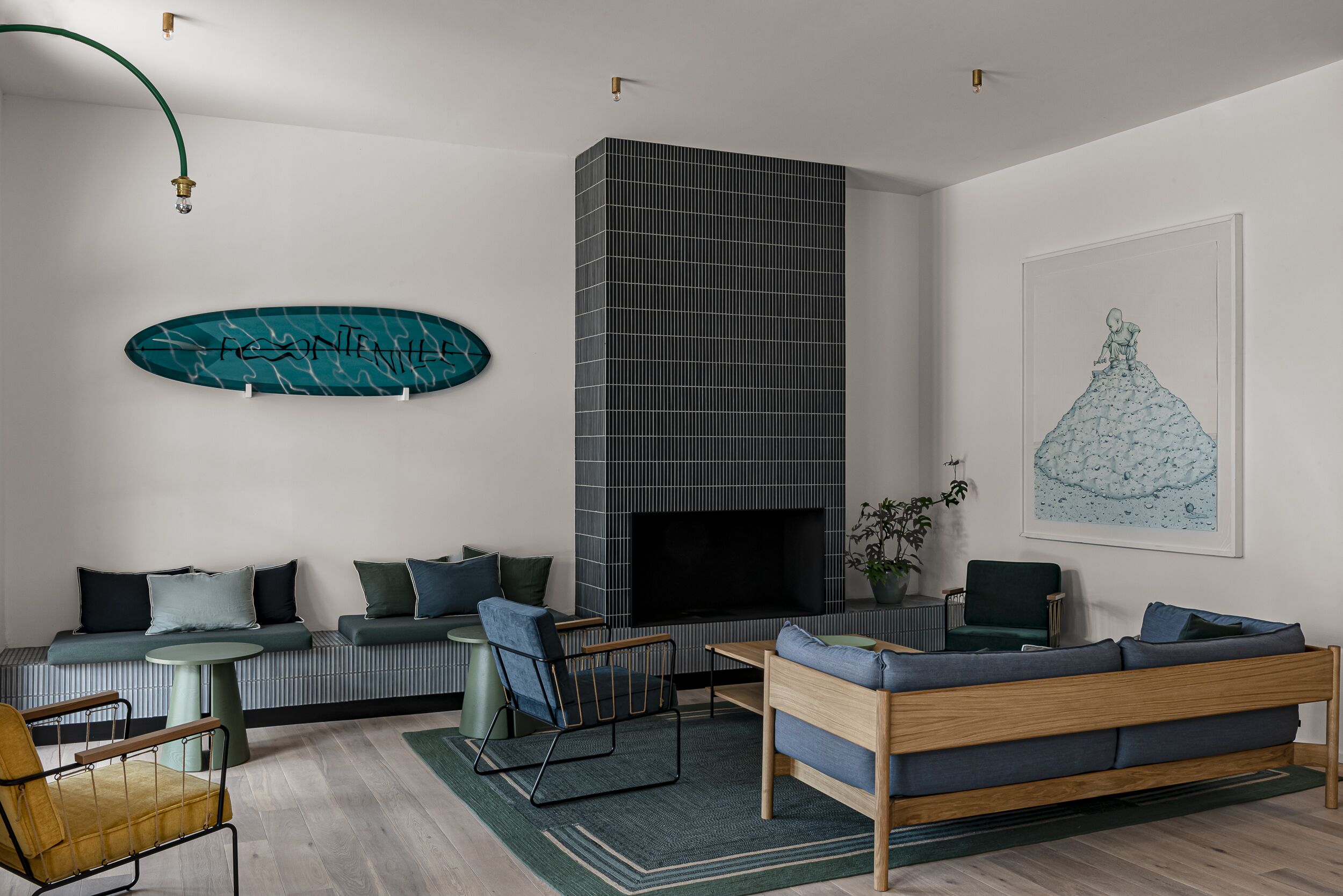 Un salon moderne avec un canapé, des fauteuils, une cheminée et un grand tableau abstrait.
