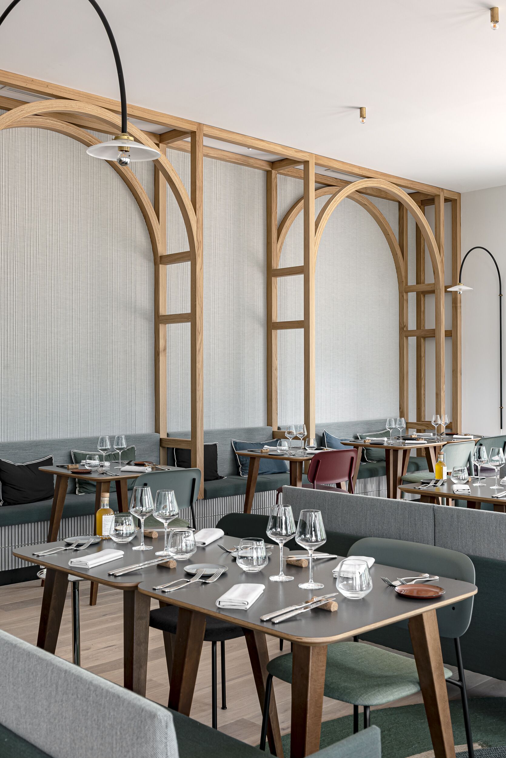Un espace de restauration moderne avec des poutres en bois, des sièges rembourrés de couleur grise et des tables dressées pour le repas.
