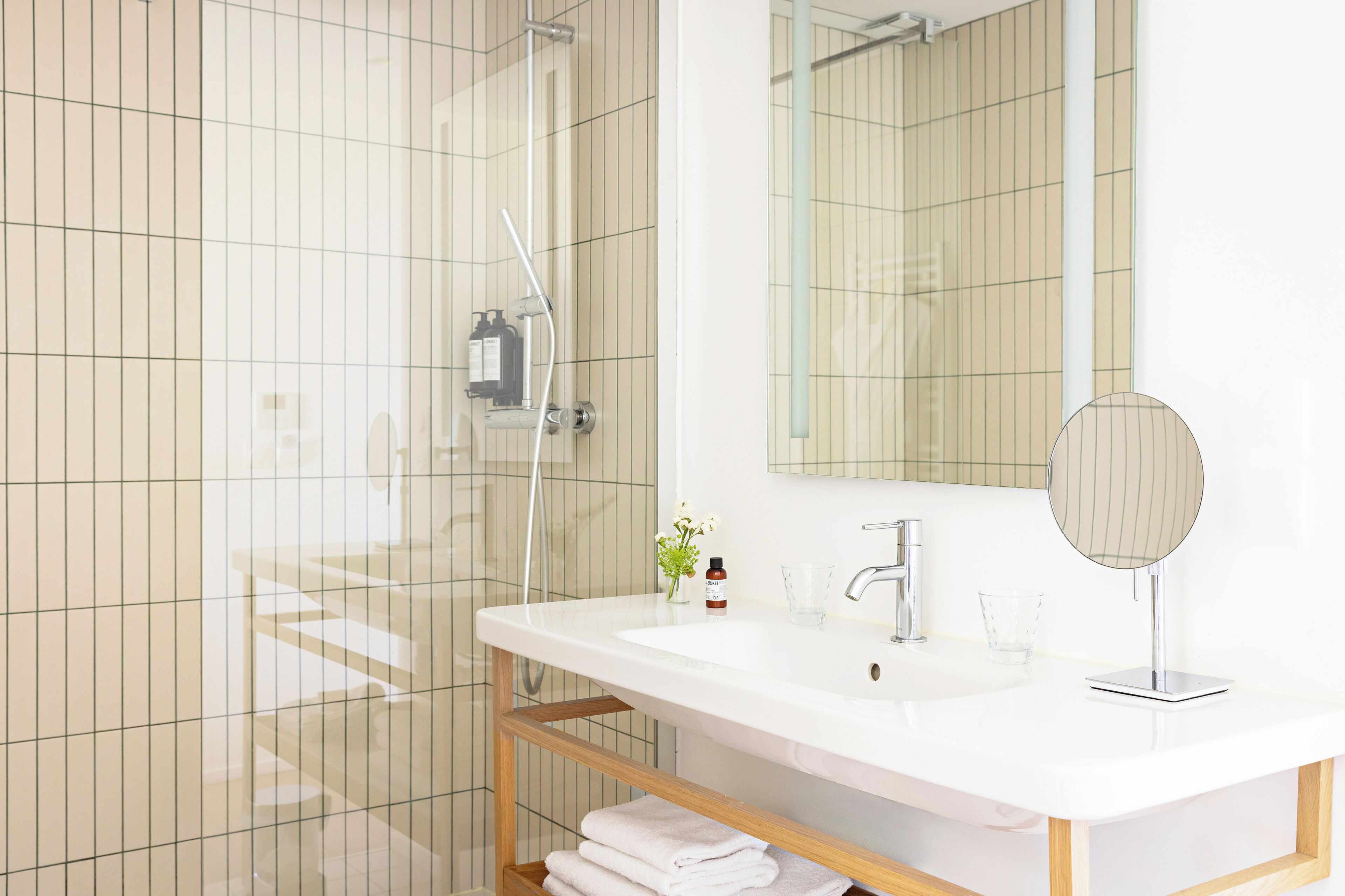 A modern bathroom with a white sink, mirror, and glass shower enclosure.