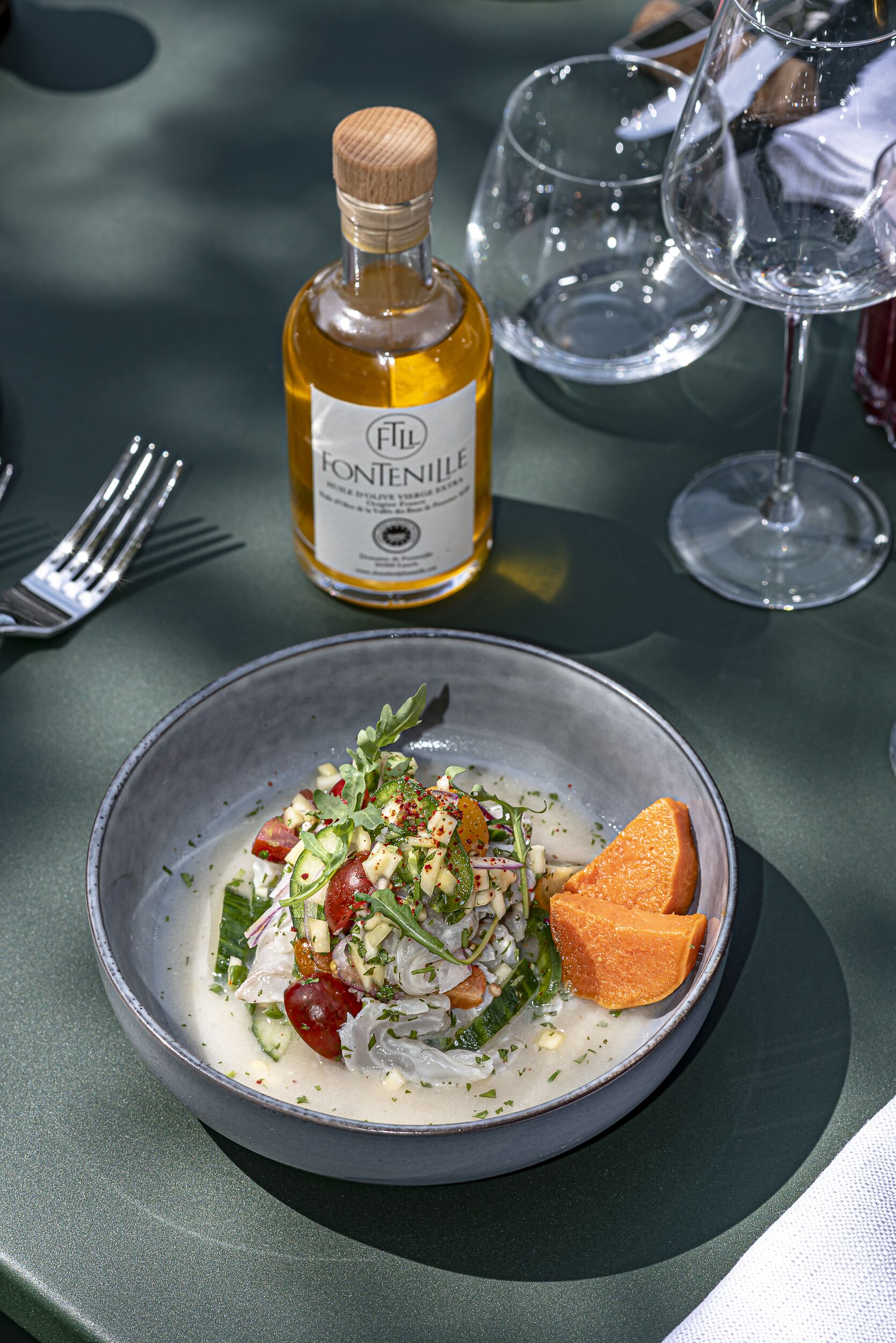 A table with a bottle of Fontenille wine, a glass of wine, and a bowl of food.