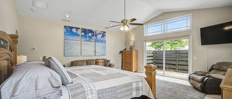 A bedroom with a bed, a ceiling fan, a window, and a TV.