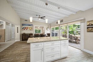 A spacious kitchen with white cabinets, a granite countertop, and a ceiling fan. - Lido Sands - 213   “Lido Key” (Sarasota)