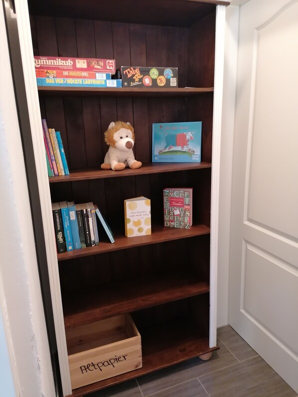 A wooden bookshelf with various books, a plush toy, and a small box labeled "Retopapier". - Sea time. Newly renovated apartment with garden in a quiet, central residential area (Norden)