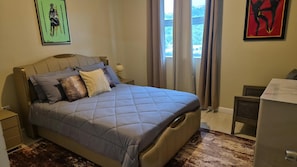 A bedroom with a bed, nightstands, a dresser, and artwork on the walls.