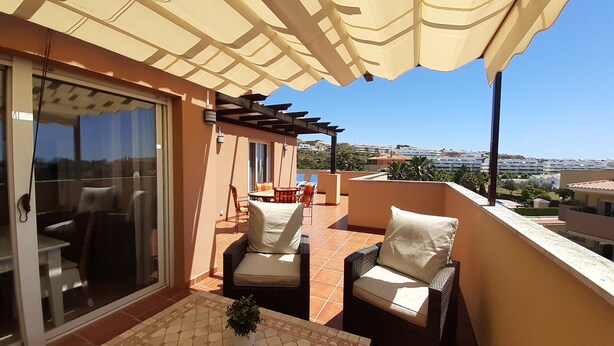 A balcony with wicker chairs and a table, a sliding glass door, and a view of the city. - Center La Cala De Mijas, penthouse,terrace 100 m², near beach and town center (LA CALA DE MIJAS)