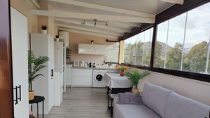A modern kitchen with a washing machine, a microwave, and a sink. There is a grey sofa and a window with a view of trees and hills. - Center La Cala De Mijas, penthouse,terrace 100 m², near beach and town center (LA CALA DE MIJAS)