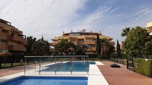 A swimming pool area with a clear view of a multi-story building in the background. - Center La Cala De Mijas, penthouse,terrace 100 m², near beach and town center (LA CALA DE MIJAS)