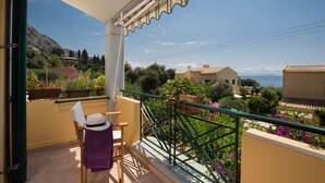 Ein Balkon mit Blick auf eine Hügellandschaft und das Meer.