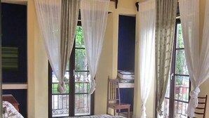 Une chambre à coucher avec un lit, un ventilateur de plafond, un climatiseur et des rideaux.