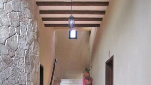 Un couloir avec un mur en pierre, un banc en bois et un escalier doté d’une rampe rose.