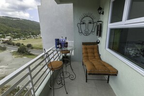 Een balkon met een comfortabele stoel, een tafel met stoelen en een wandlamp.