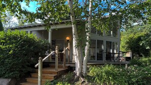 A house with a porch, wooden steps, and a garden with rocks and plants.