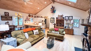 A spacious living area with a high ceiling, wooden beams, and a central island.