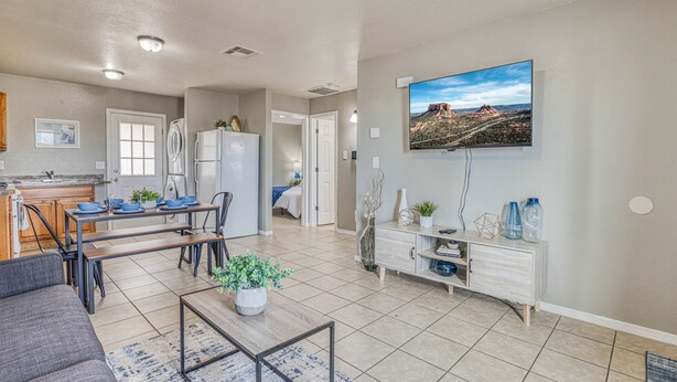 A modern living room with a dining area, kitchen, and a large TV mounted on the wall. - ☕ BY FORT BLISS: LAUNDRY, SECURITY SYSTEM, REFRIGERATION, KING BEDS (El Paso)