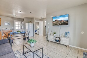 A modern living room with a dining area, kitchen, and a large TV mounted on the wall. - ☕ BY FORT BLISS: LAUNDRY, SECURITY SYSTEM, REFRIGERATION, KING BEDS (El Paso)