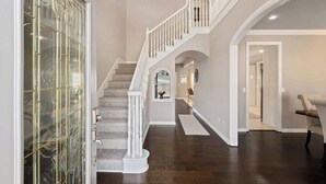 A spacious interior with a grand staircase, a glass door, and a view into another room.
