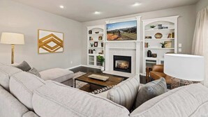 A modern living room with a fireplace, a sofa set, and built-in shelving.