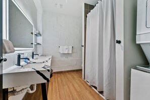 Ein Badezimmer mit Waschbecken, Spiegel und Handtuchhalter. Eine Duschvorhang und eine Toilette sind zu sehen.