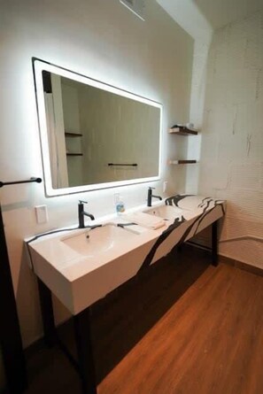 Ein modernes Badezimmer mit zwei Waschbecken, einem großen Spiegel und Holzboden.