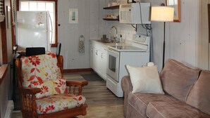 A compact kitchen with a refrigerator, microwave, stove, and sink.