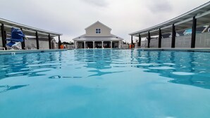 Piscina com área coberta e um edifício ao fundo.
