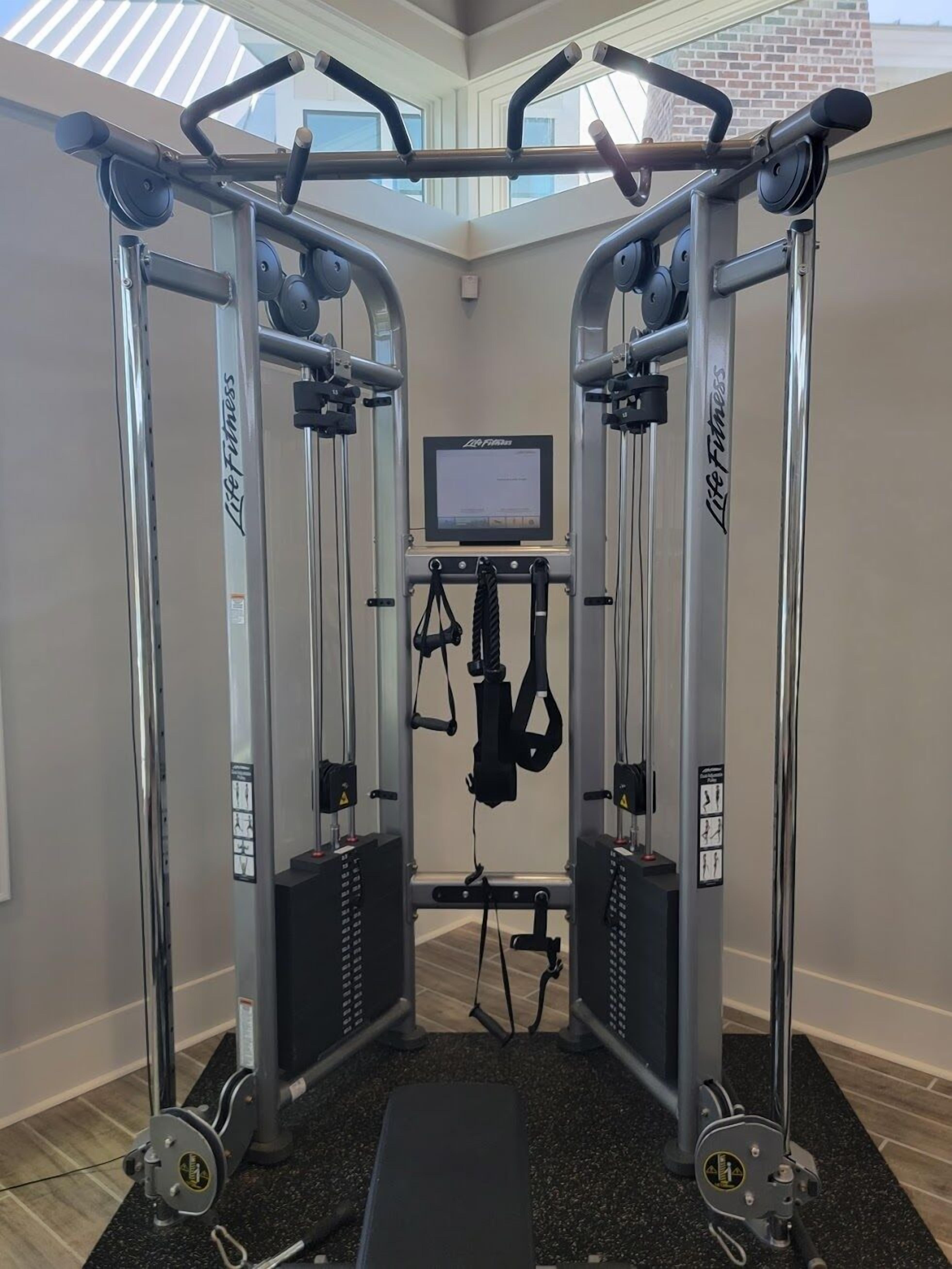 Un gimnasio con pared espejada, cinta de correr y máquina de pesas.