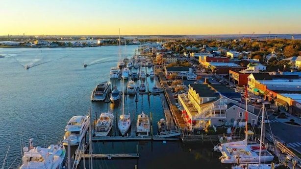 Uma marina com vários barcos atracados, um edifício à beira-mar e uma vista clara da água.