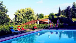 Una piscina con lettini e un edificio sullo sfondo.