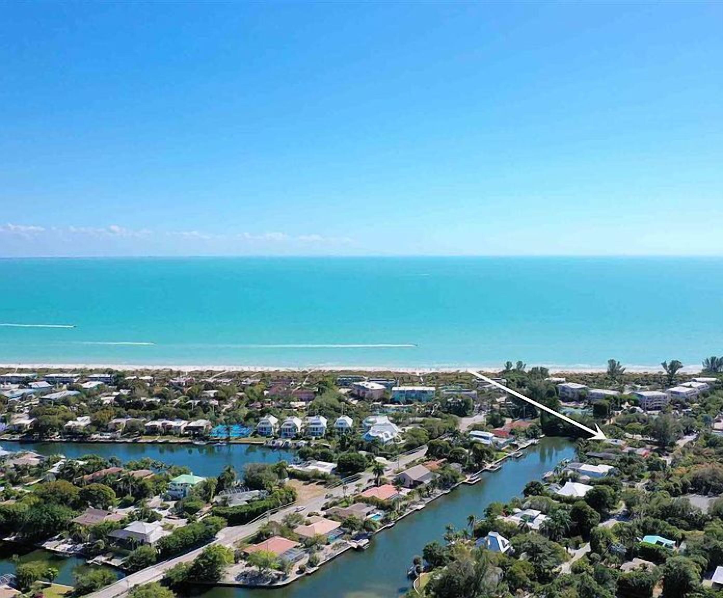 Vista aérea de una zona residencial costera con un puerto deportivo, casas y una playa.