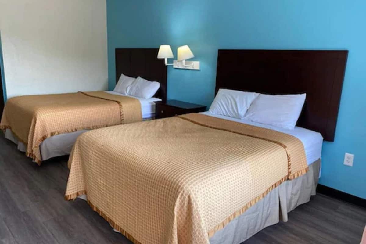 Two single beds with headboards, a nightstand with a lamp, and a blue wall.