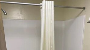 A bathroom with a shower, toilet, and a towel rack. - Havelock Inn & Suites (Havelock)