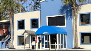 A building with a blue awning labeled "OFFICE" and a parking lot in front. - Havelock Inn & Suites (Havelock)
