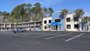 A motel with a parking lot, a blue awning, and a building with multiple windows. - Havelock Inn & Suites (Havelock)