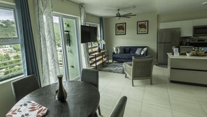 Een moderne woonkamer met een eethoek, een bank, een televisie en een keuken met een koelkast en magnetron.