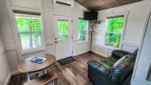 A cozy room with a wooden ceiling, a leather sofa, a small table, and a TV mounted on the wall.